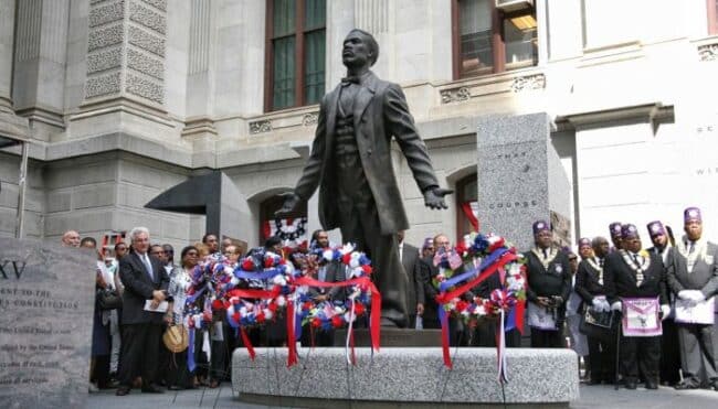 Statue of Octavius Catto with people gathered around it