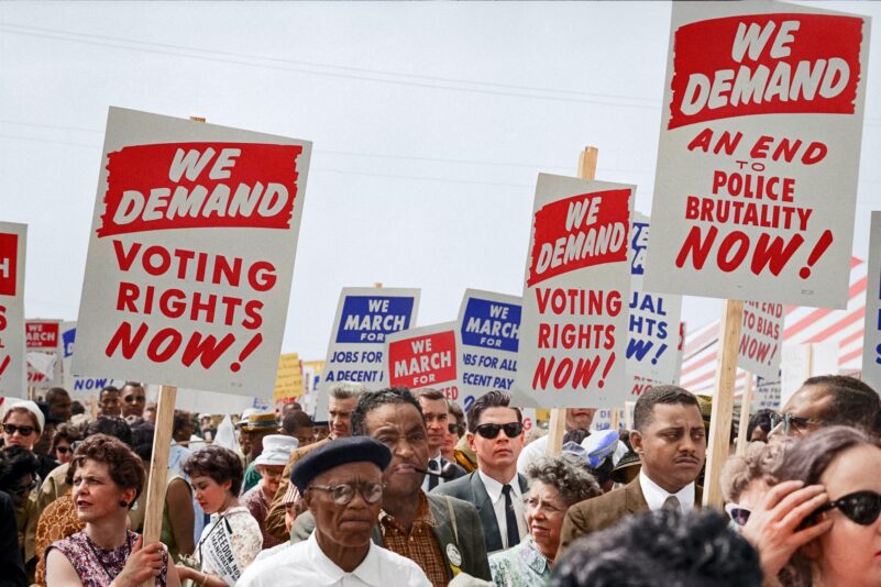 people marching with signs reading we demand voting rights now! 
