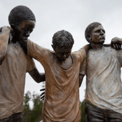 a statue of three boys holding up the one in the middle