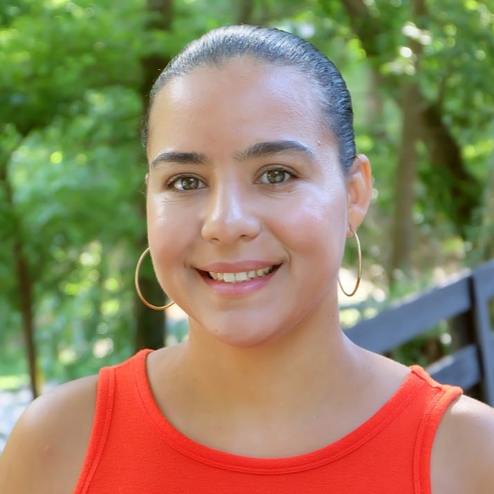 headshot of woman in orange tank top outdoors