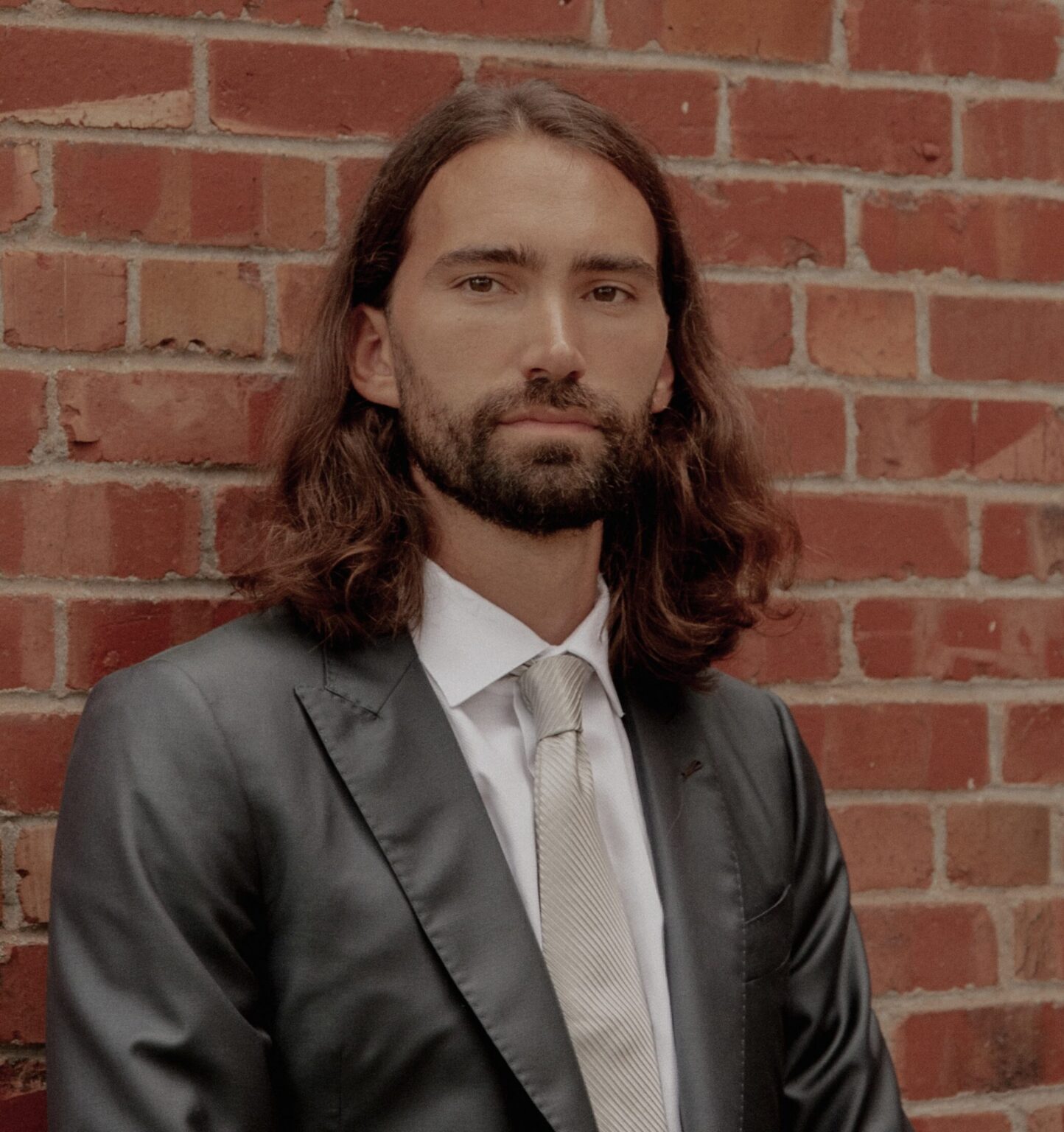 photo of man in suit against brick wall