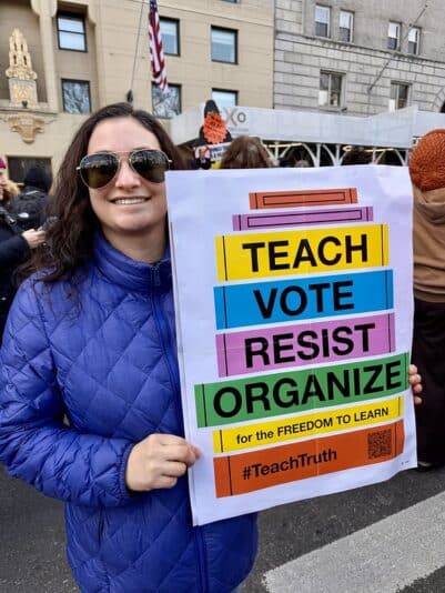 woman holding teach vote resist organize poster at protest